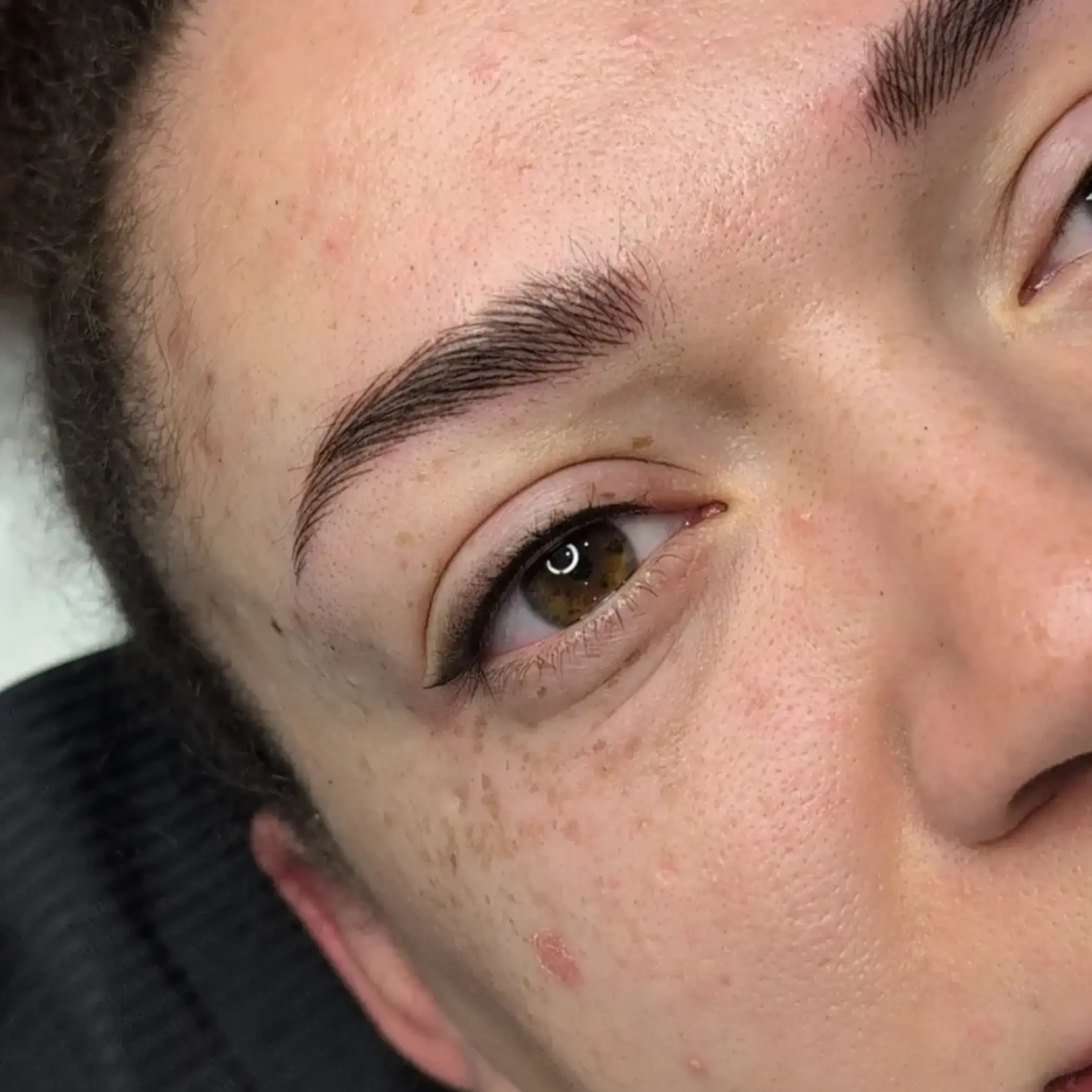 technician shaping brows with pencil
